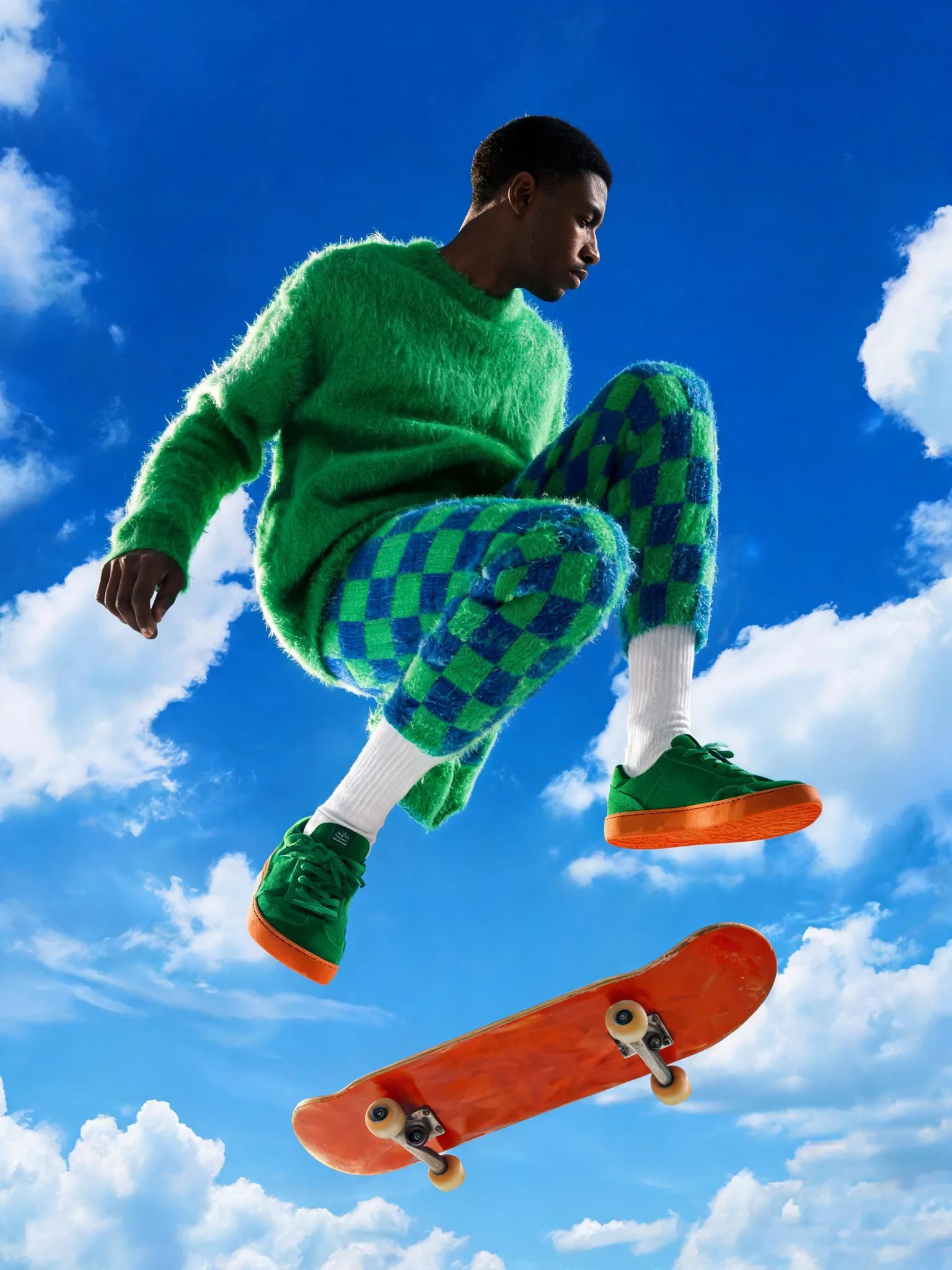 Subject: A tall slim Black male model with short cropped hair and clean-shaven face, profile view looking down, mid-air stepping pose with one knee raised high, wearing an oversized bright grass-green fuzzy knit crewneck sweater and matching green-and-blue checkerboard fluffy knit trousers, crisp white ribbed crew socks, chunky green suede low-top sneakers with vivid orange rubber soles

Scene: Surreal open sky setting, deep cobalt blue backdrop dotted with soft painterly white cumulus clouds, a large glossy orange-red skateboard deck with cream-colored wheels entering the frame at the bottom, floating dreamlike stage with no horizon, bright midday atmosphere

Composition: Vertical 3:4 portrait crop, full-body subject slightly off-center, low-angle upward viewpoint emphasizing levitation, head cropped near the top edge, diagonal leg lines leading toward the skateboard in the lower foreground, generous negative space of sky around the figure

Lighting: Hard directional sunlight from the upper left, crisp defined shadows on the face and knit folds, gentle rim light along the shoulder and arm, soft even fill on the clouds, warm-neutral daylight color temperature around 5500K

Color: High-saturation triadic palette of cobalt blue, acid grass green and orange-red accents, white clouds and socks as bright breaks, strong complementary contrast, punchy editorial saturation

Style: Contemporary fashion editorial meets surrealist collage, retro 1990s streetwear campaign feel, playful pop-art staging reminiscent of Tyler Mitchell and analog studio backdrop painting, hyperreal yet stylized

Camera: Medium format digital, 80mm lens equivalent, f/8, 1/500s, ISO 100, deep depth of field with sharp subject and softly rendered clouds, subtle film grain and slight halation

Details: Visible fluffy mohair fiber texture and pilling on knitwear, chunky checkerboard weave, suede nap on sneakers